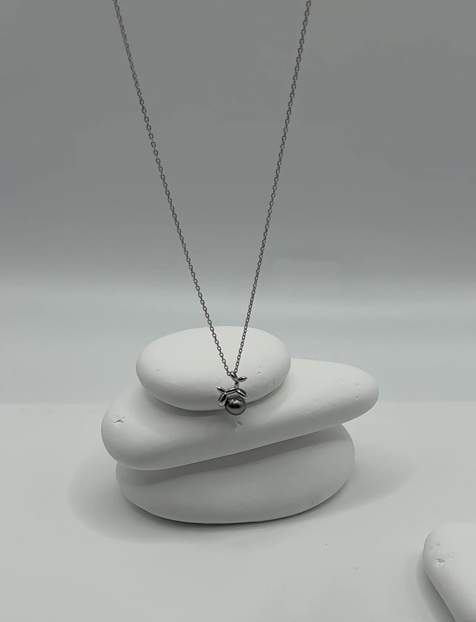 Video showing playful balloon dog pendant with Tahitian keshi pearl swaying gently, displaying the contemporary charm design and natural pearl lustre