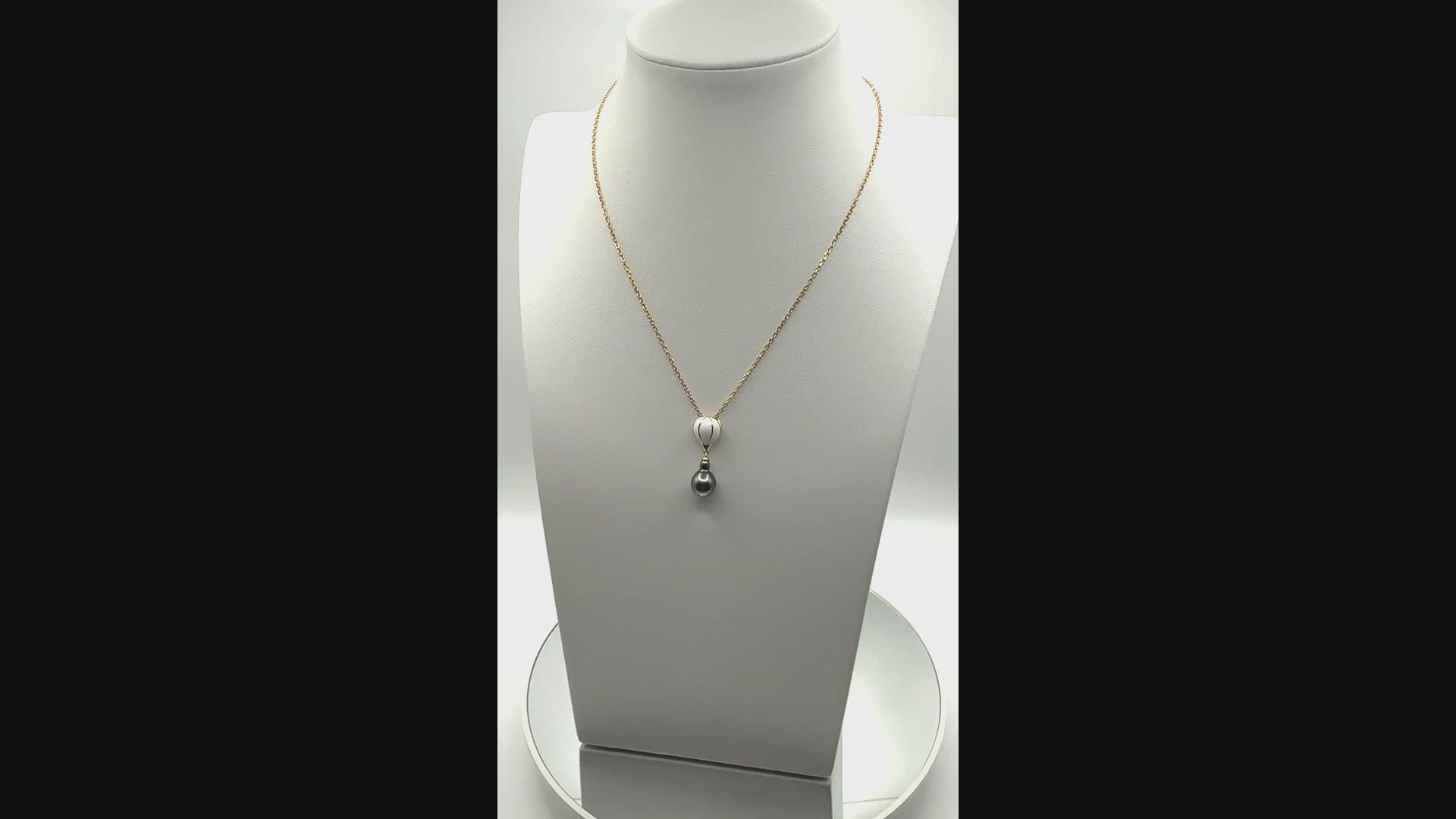 Short video showing a gold-plated 925 silver necklace with a white enamel hot air balloon charm and teardrop Tahitian pearl pendant, gently rotating to reveal lustre, charm detail, and chain movement.
