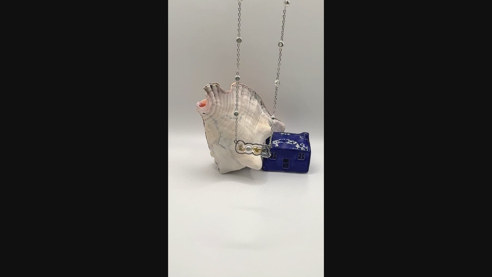 Video showing sterling silver 'LOVE' pendant necklace with mixed keshi pearls suspended in air, demonstrating the movement and colour variation of the letter pendants