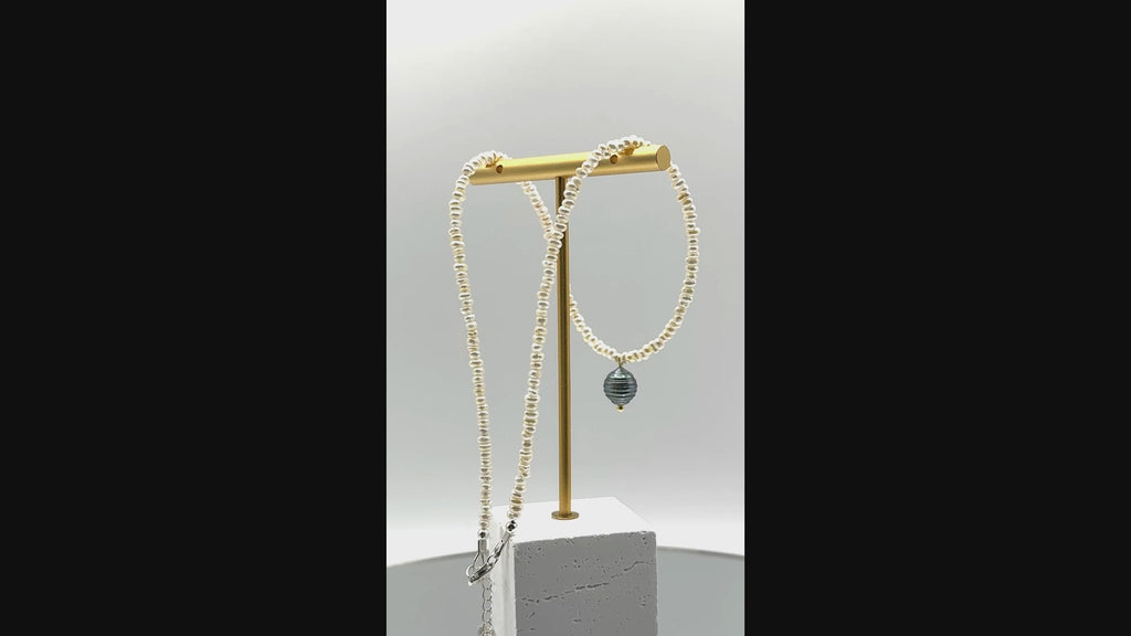 Video showing white seed pearl choker with green Tahitian baroque pearl pendant rotating to display all angles of the baroque pearl and delicate seed pearl construction