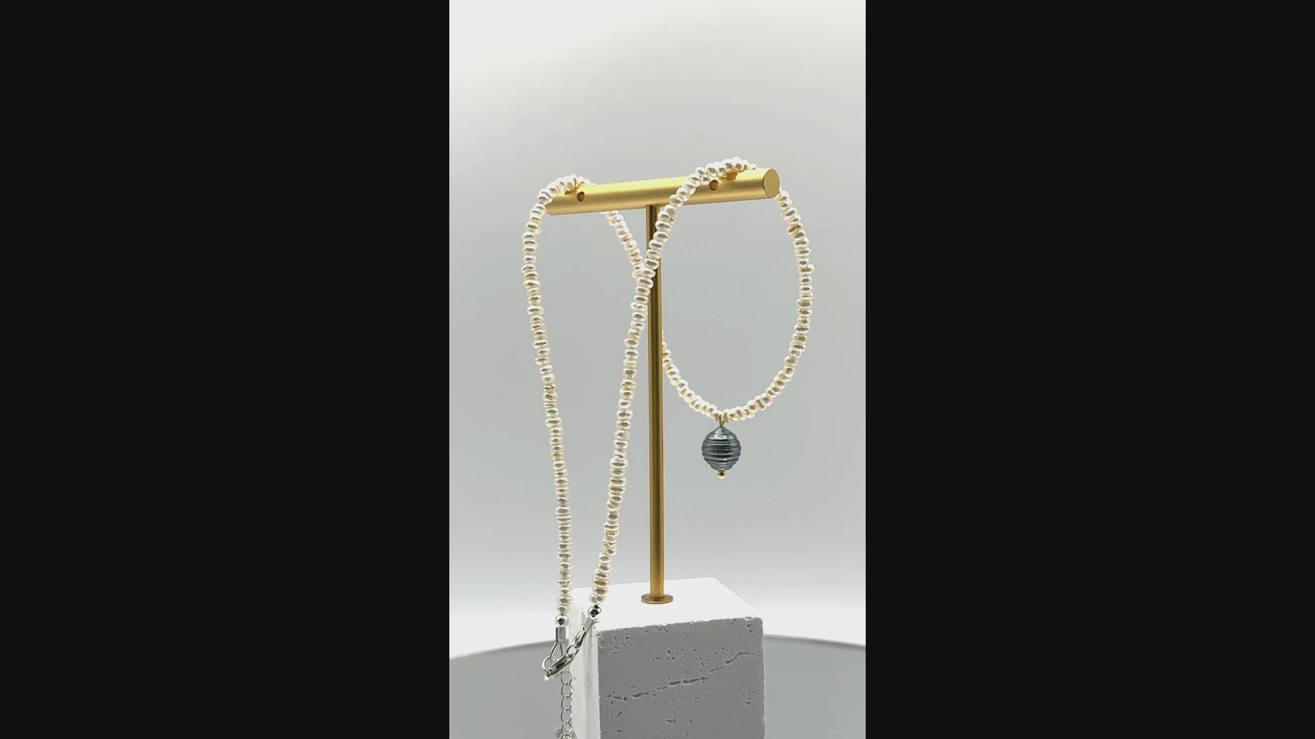 Video showing white seed pearl choker with green Tahitian baroque pearl pendant rotating to display all angles of the baroque pearl and delicate seed pearl construction