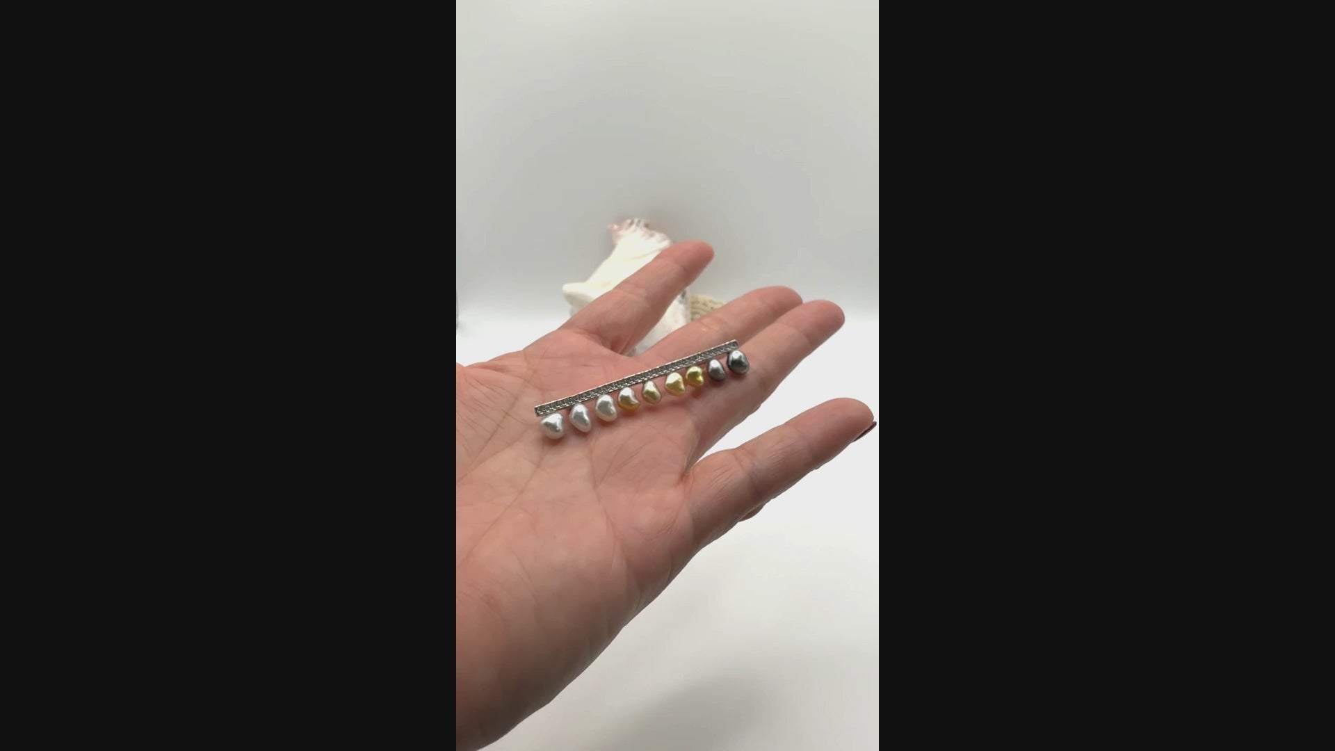 Video showing sterling silver bar pin brooch with heart-shaped keshi pearls held in palm of hand, demonstrating the size and beauty of the mixed coloured heart pearls
