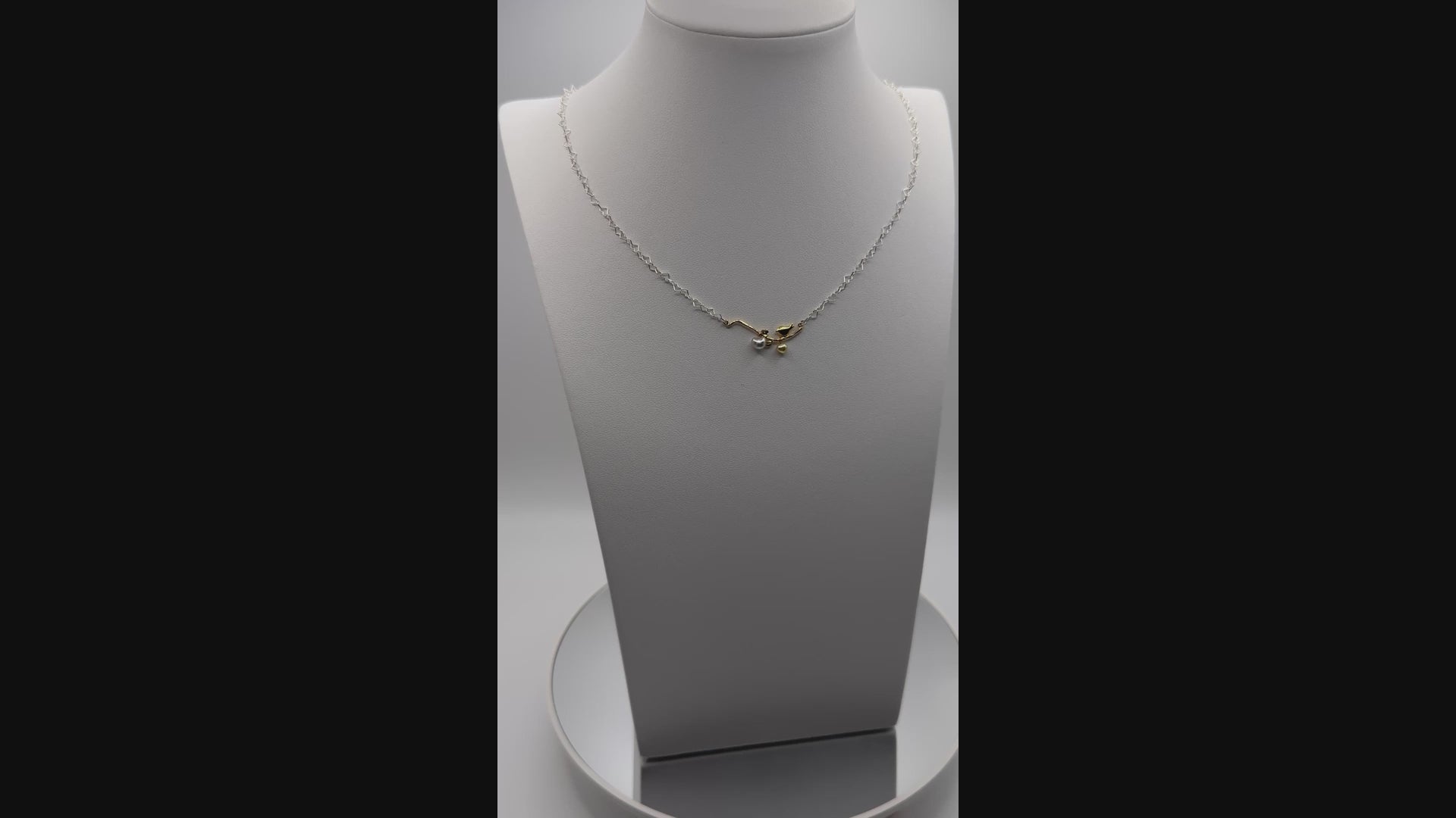 Rotating video of 'Love me, Love you' necklace highlighting movement of heart-shaped pearls and shimmer of gold bird pendant on silver heart chain
