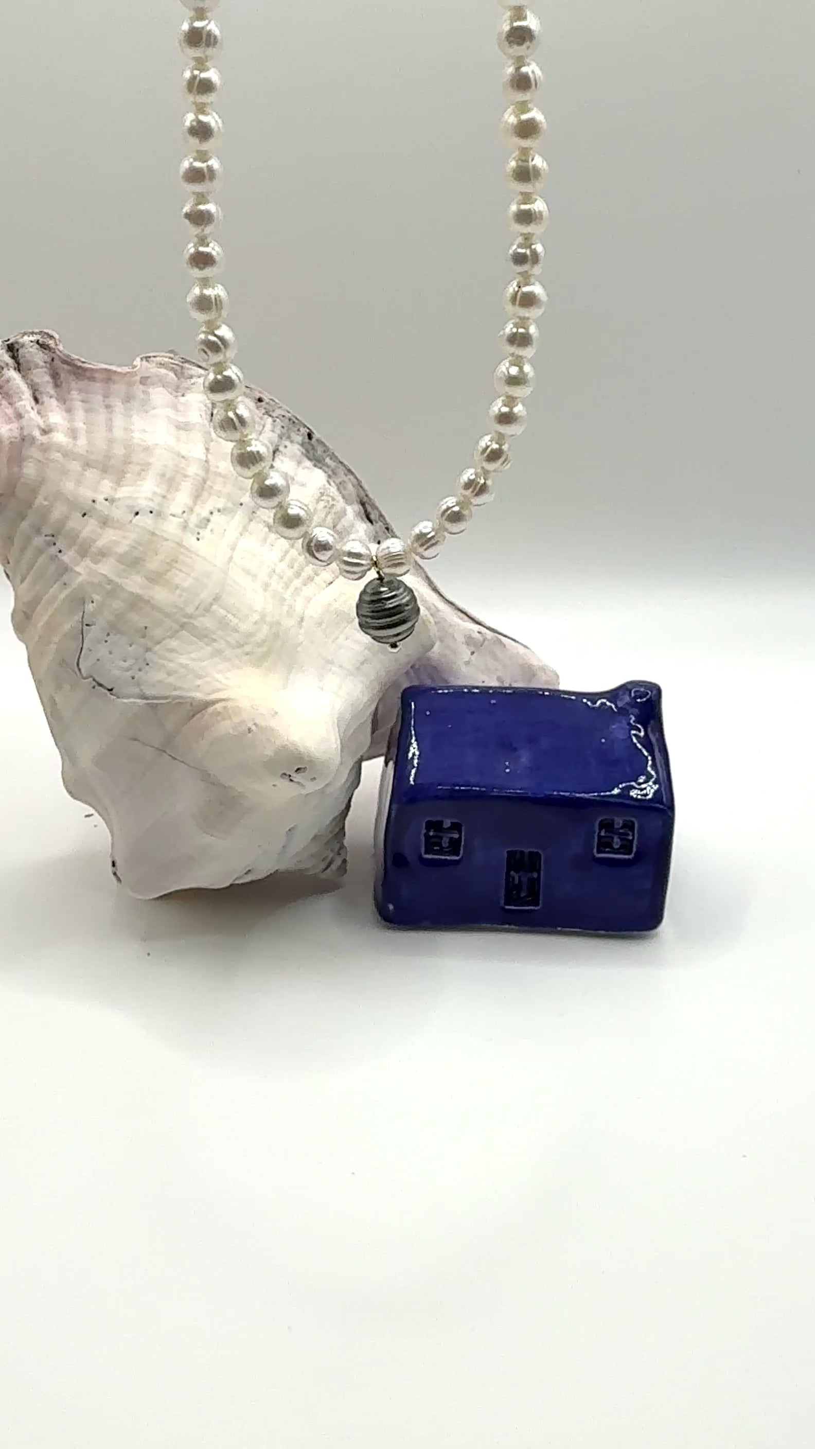 Video showing Circle Dance necklace movement with Tahitian circled pearl charm and white freshwater circled pearls dangling in air displaying natural lustre and texture