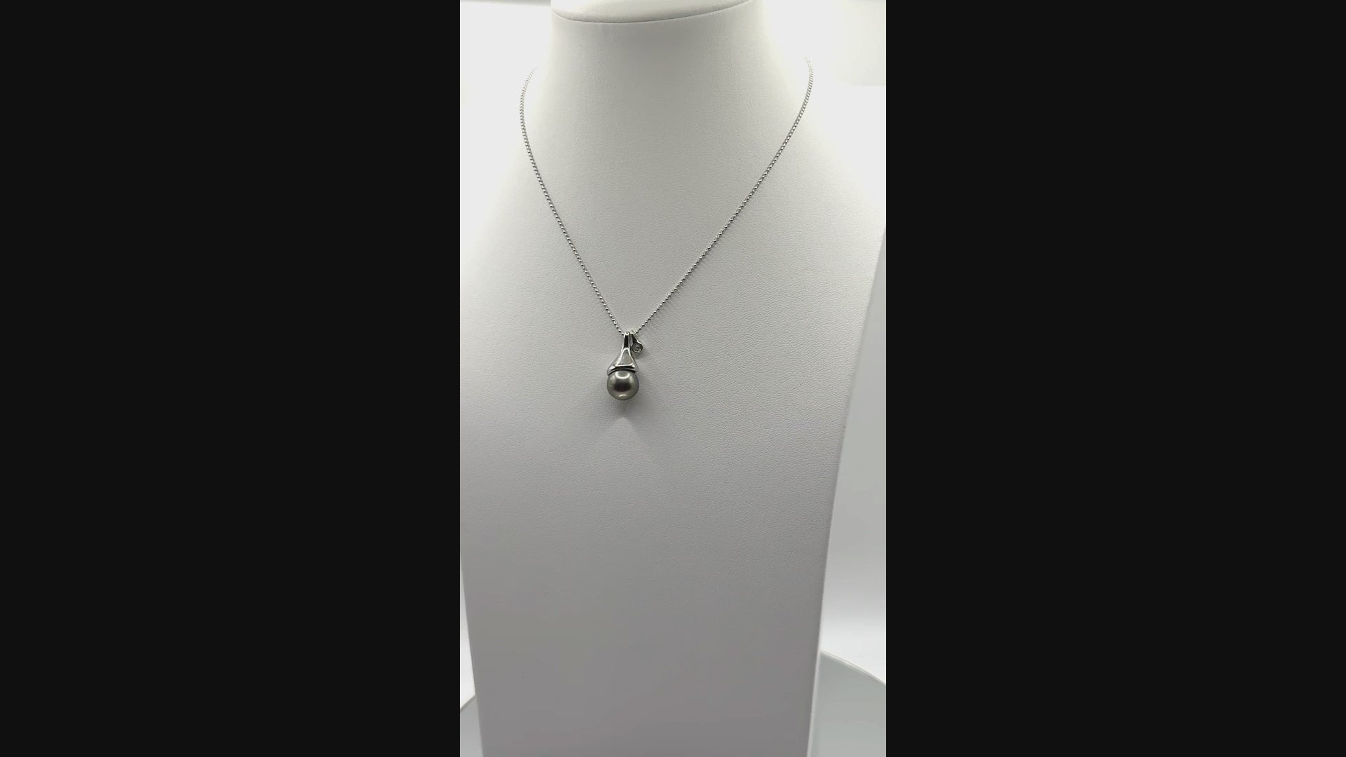 Video showing sterling silver ball chain necklace with Tahitian pearl pendant rotating to display all angles of the pearl and contemporary setting