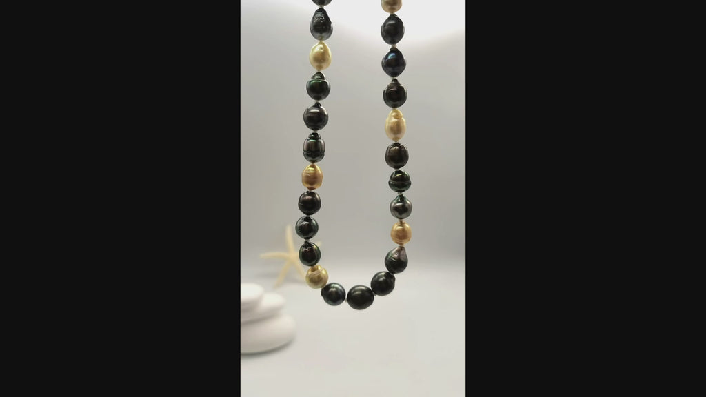 Video of multicoloured baroque pearl necklace suspended and gently moving in the air, displaying the beautiful variety of dark green, black, golden and white baroque pearls in fluid motion