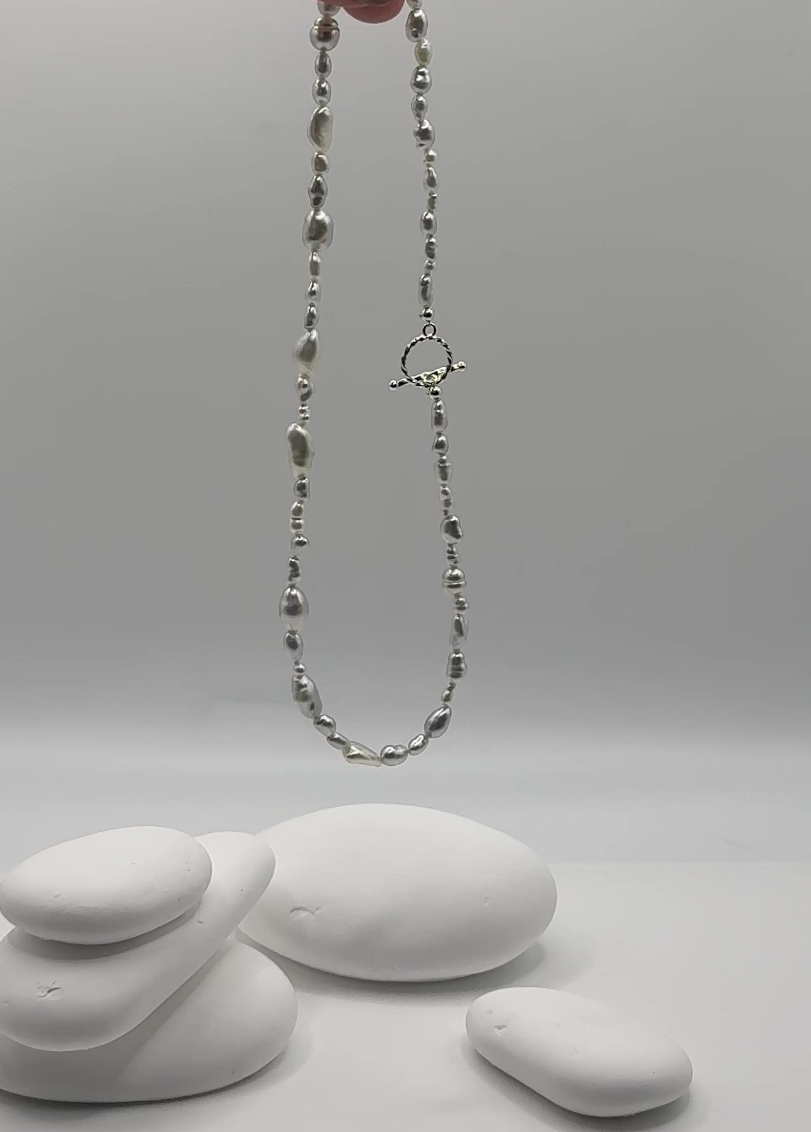 South Sea white keshi strand suspended in air showing natural movement and flow of varied organic shapes with sterling silver OT toggle clasp swaying gracefully 