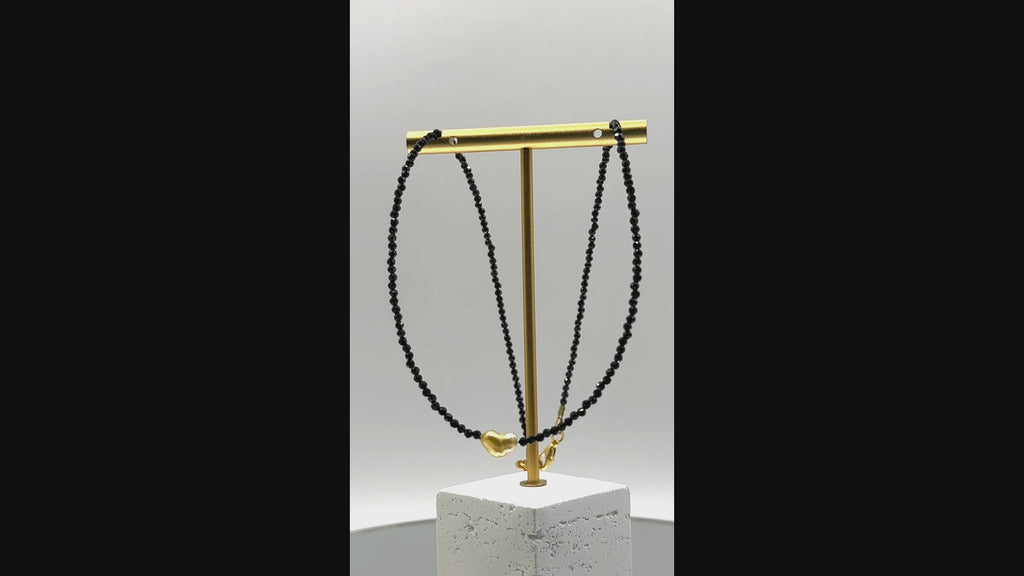 Video showing golden South Sea heart keshi pearl choker with black spinel beads rotating to display all angles of the heart-shaped pearl centrepiece