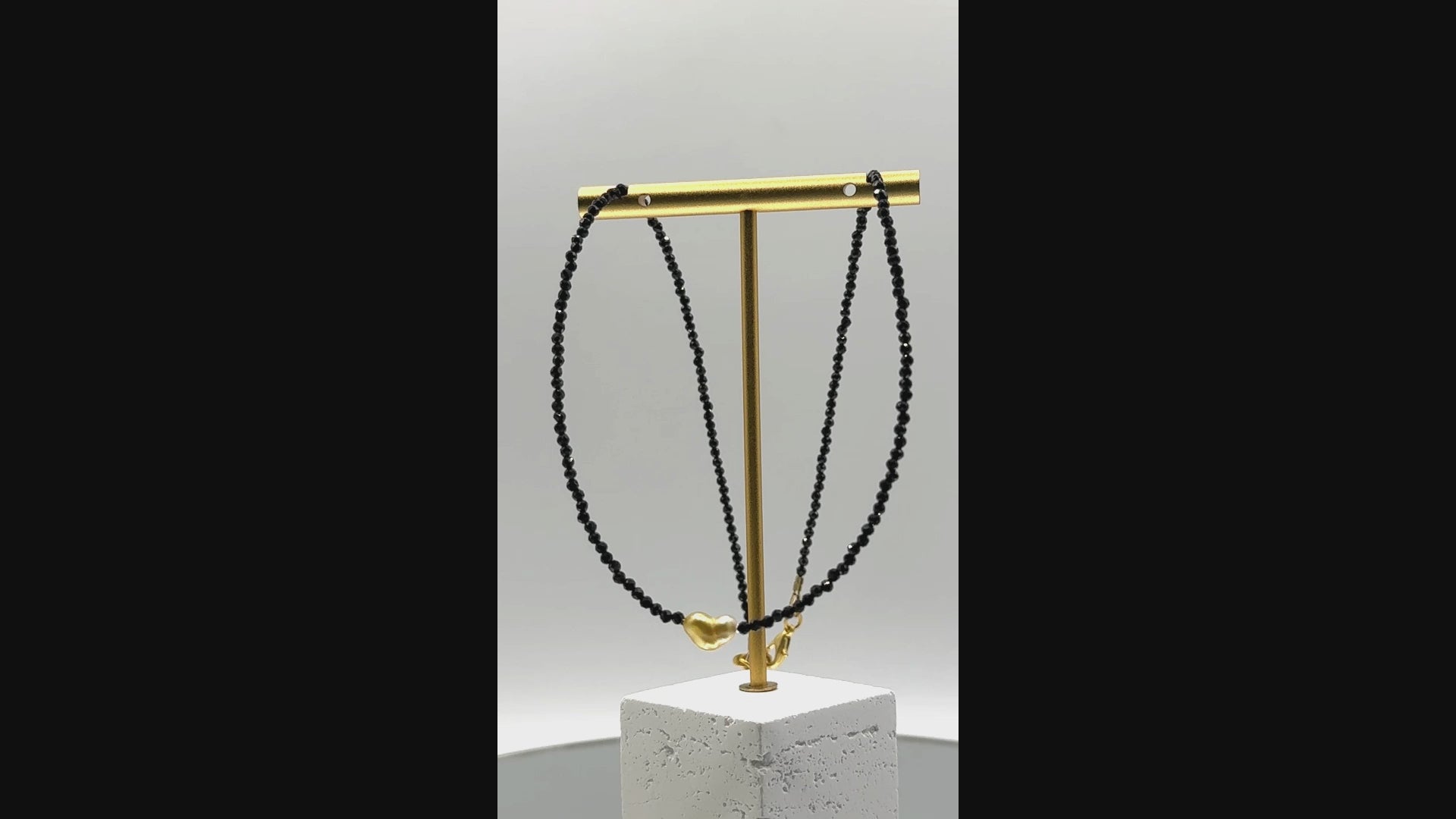 Video showing golden South Sea heart keshi pearl choker with black spinel beads rotating to display all angles of the heart-shaped pearl centrepiece