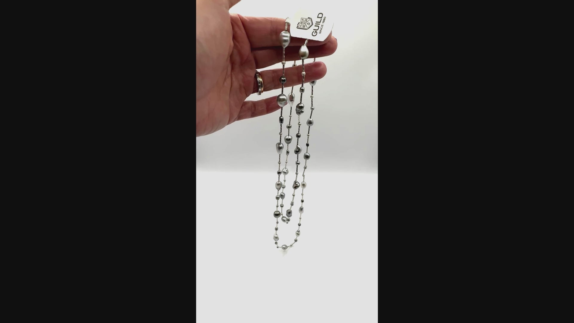 Video showing long sterling silver station necklace with Tahitian keshi pearls coiled and draped in hand, demonstrating the flow and movement of the strand