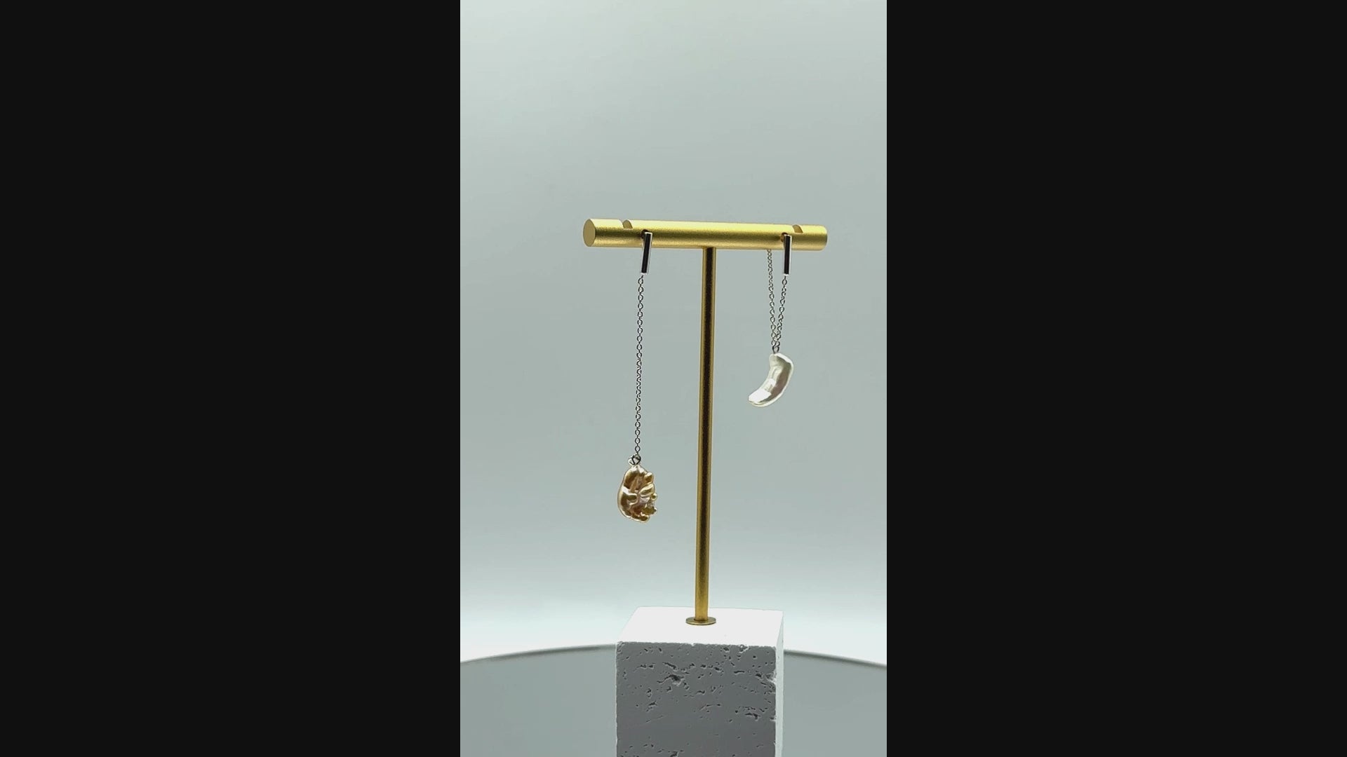 Video showing asymmetrical gold drop earrings with South Sea keshi pearls rotating to display the contrasting white and golden baroque pearls and delicate chain construction