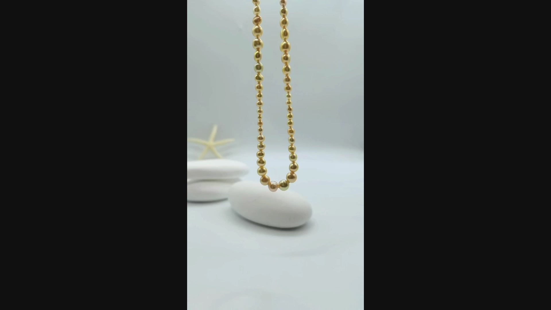 Video: Golden pearl strand necklace suspended and gently moving in the air, displaying the lustrous graduated pearls and fluid drape of the complete necklace design