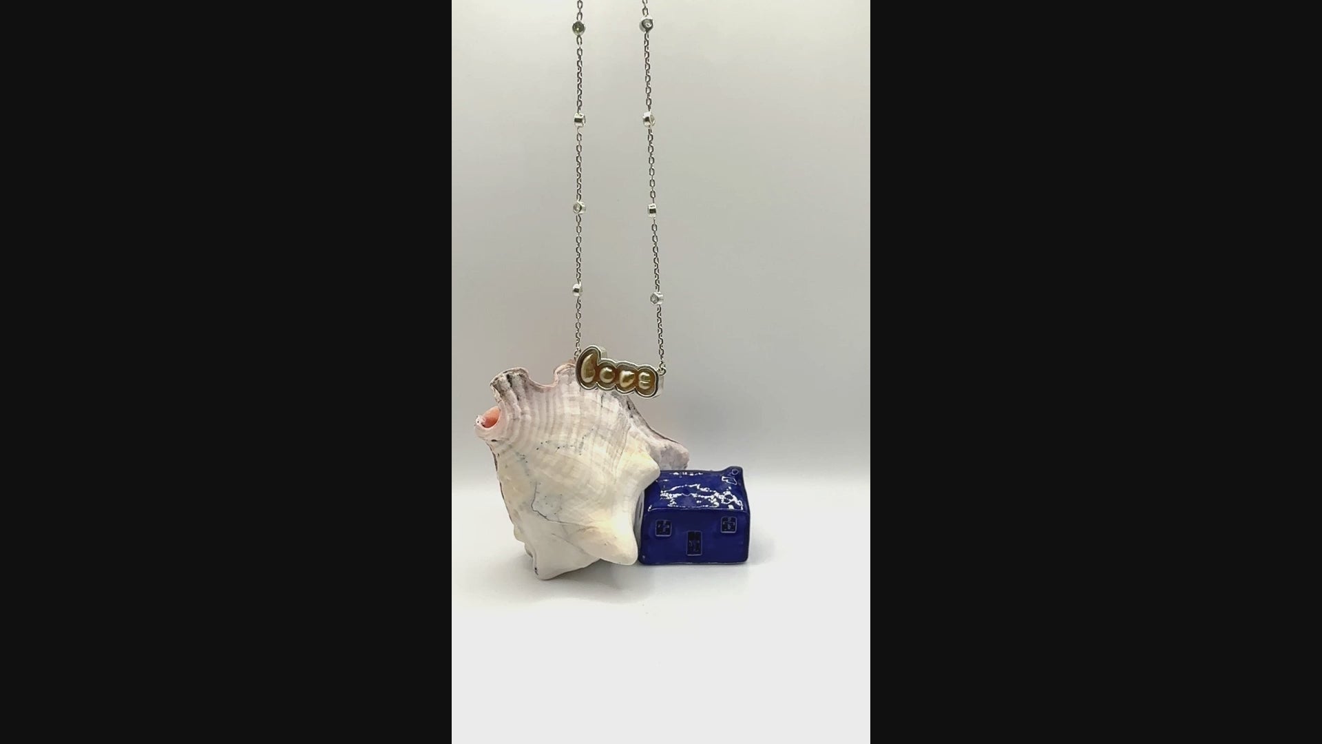 Video showing gold 'LOVE' pendant necklace with South Sea keshi pearls suspended in air, demonstrating the movement and connection of the letter pendants