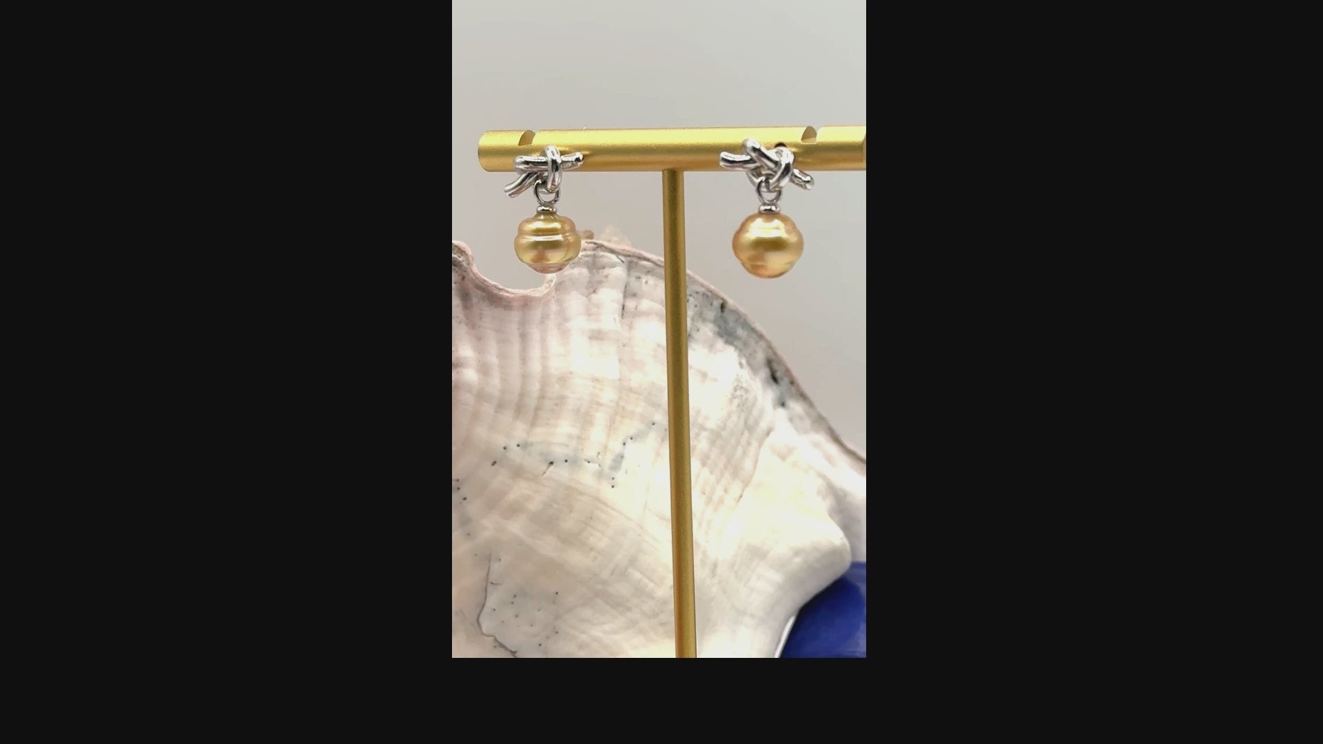 Video showing sterling silver earrings with golden South Sea pearls and decorative knot details rotating to display all angles of the pearls and silver craftsmanship