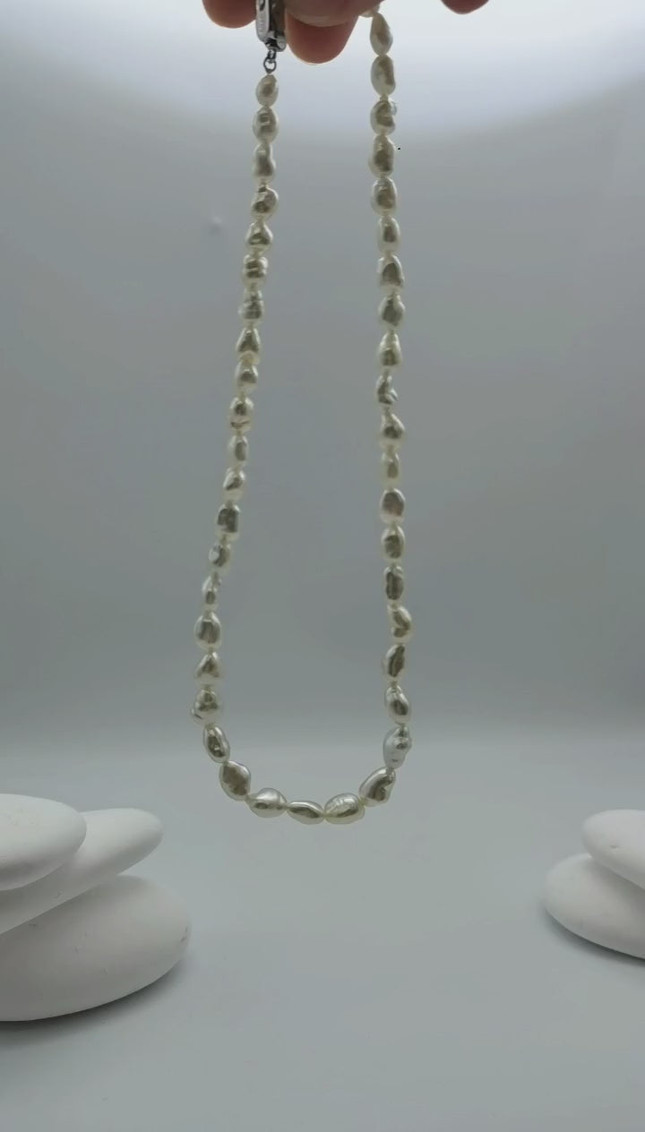 South Sea white keshi pearl strand necklace suspended in air demonstrating natural movement and drape showcasing baroque pearls lustrous finish